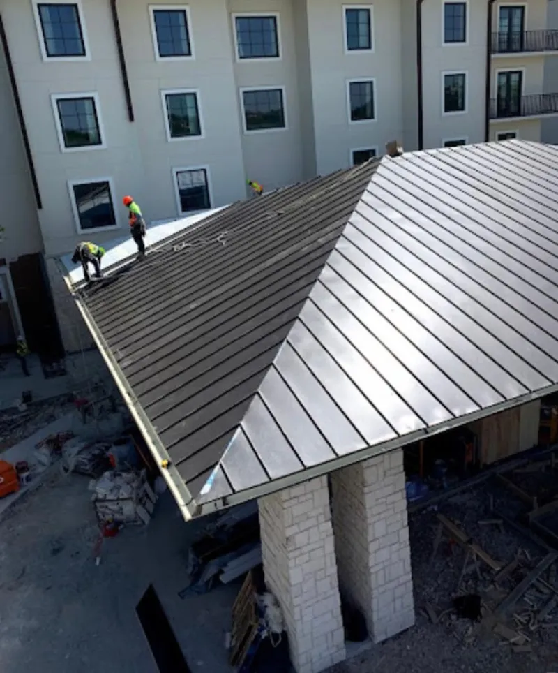 Crew installing standing seam metal roof panels on a commercial project in Belton